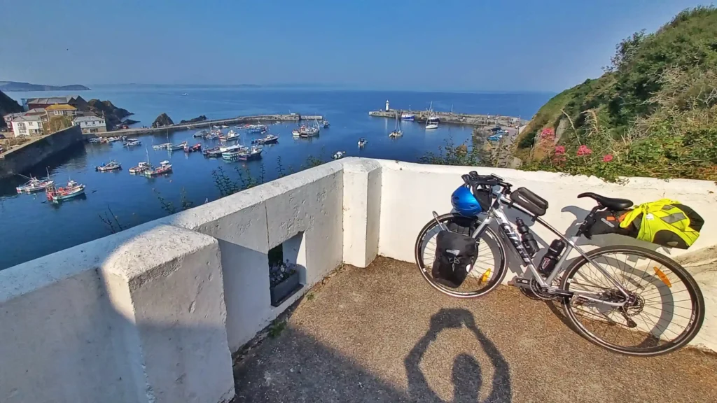 Bicycle leaning against low wall overlooking a harbour and sea on a sunny evening