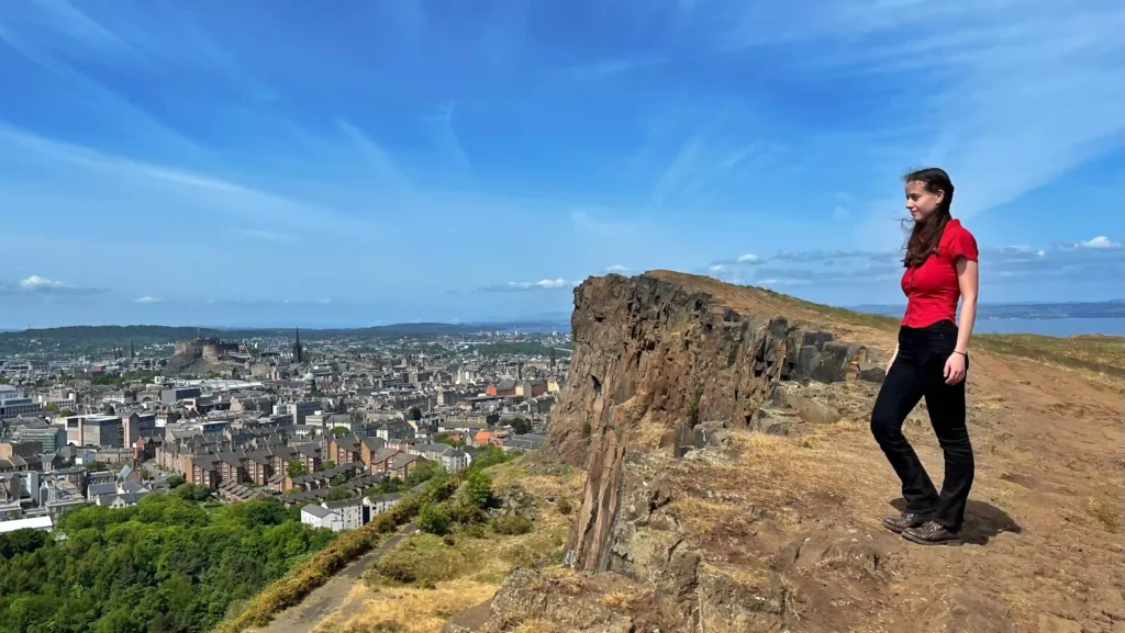 Ever Prel standing on Salisbury Crags overlooking Edinburgh city and Castle Rock on a sunny day