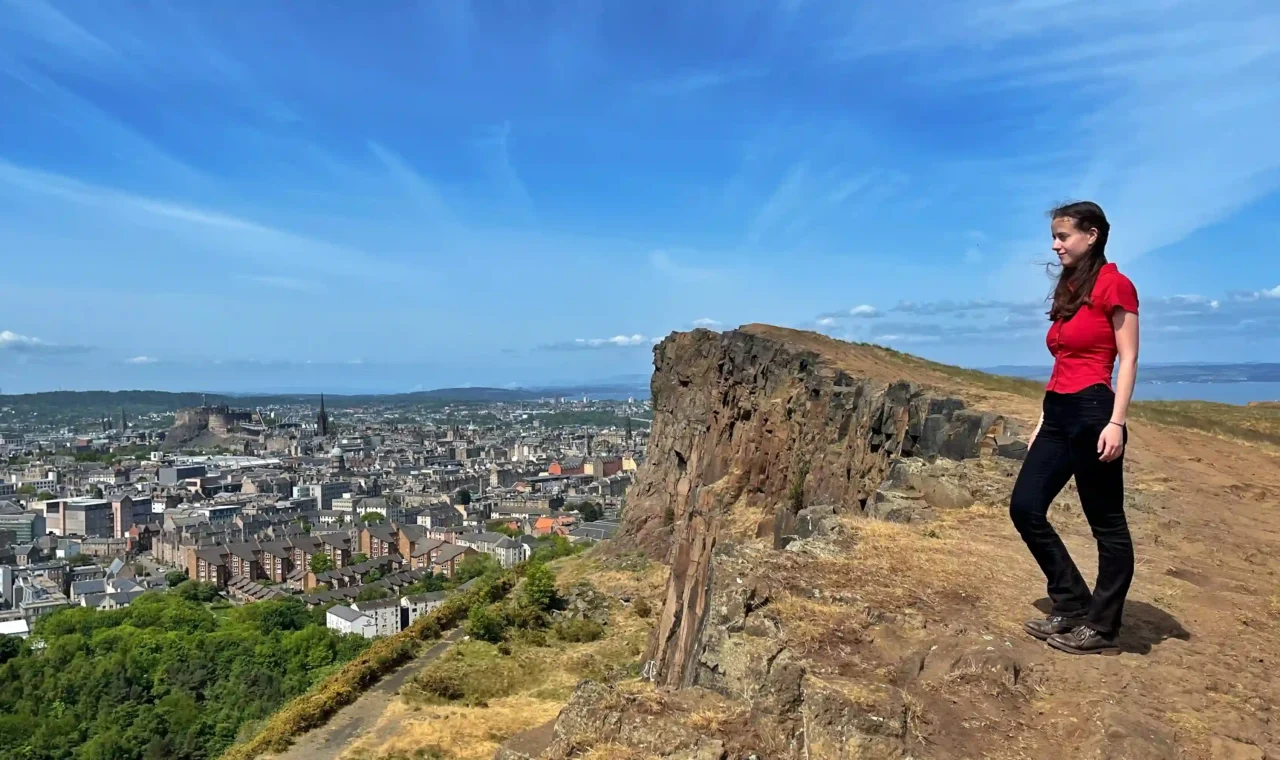Ever Prel standing on Salisbury Crags overlooking Edinburgh city and Castle Rock on a sunny day