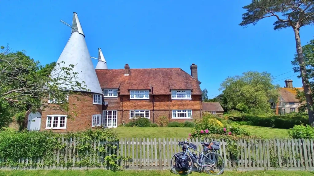 Traditional English cottage in southern England on a sunny day with a bike resting against a hedge