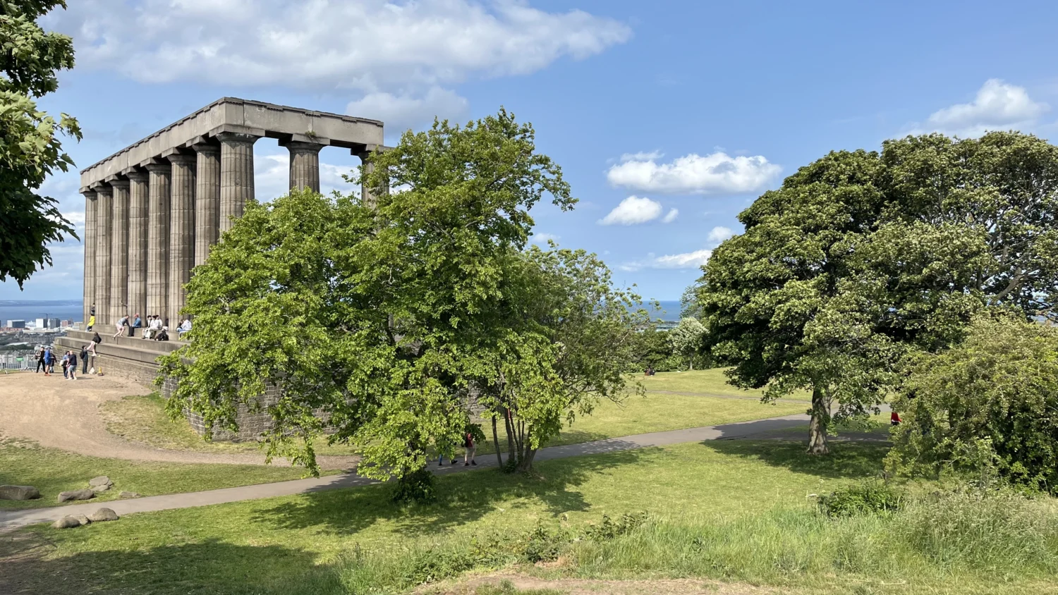Calton Hill and National Monument in Edinburgh on a sunny day with trees in foreground