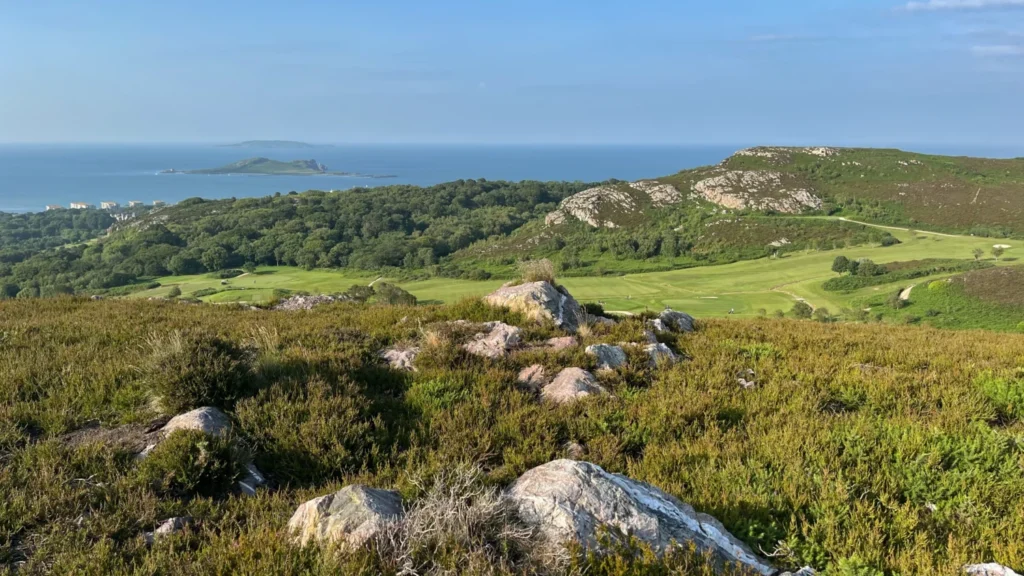 Rolling green hills of Howth in Ireland with a distant view of Ireland’s Eye and the Irish Sea