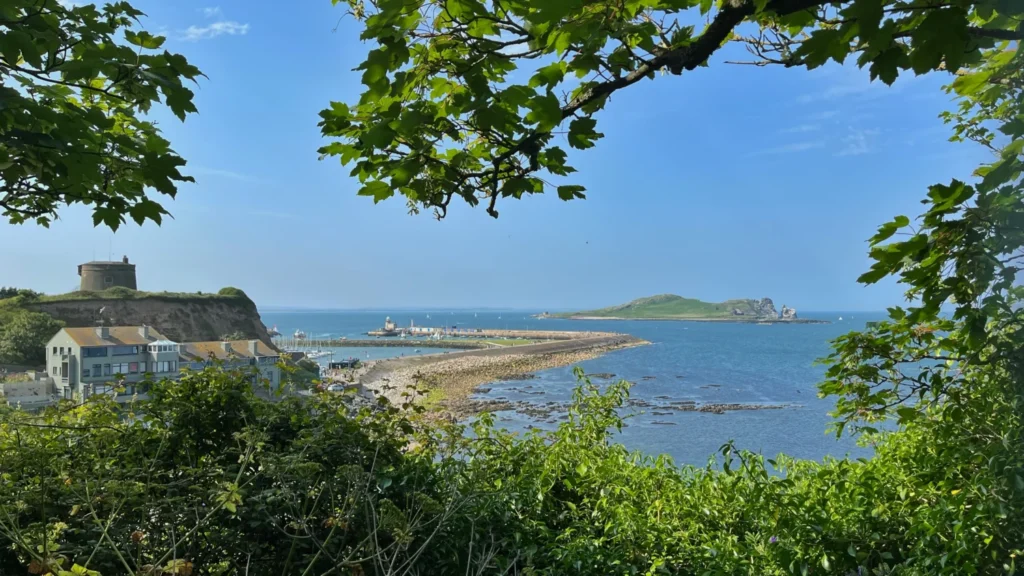 Distant view of Howth village in Ireland with Ireland’s Eye and Howth Harbour in the centre under a clear blue sky