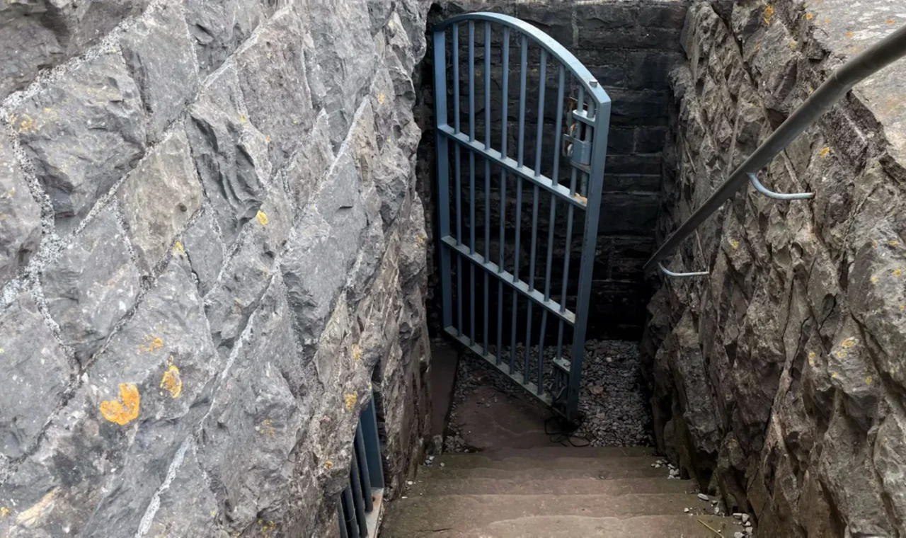 Locked metal gate blocking stone steps into a rocky cutting at Brean Down Fort