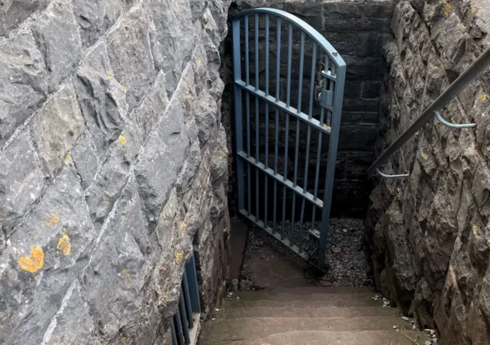 Locked metal gate blocking stone steps into a rocky cutting at Brean Down Fort