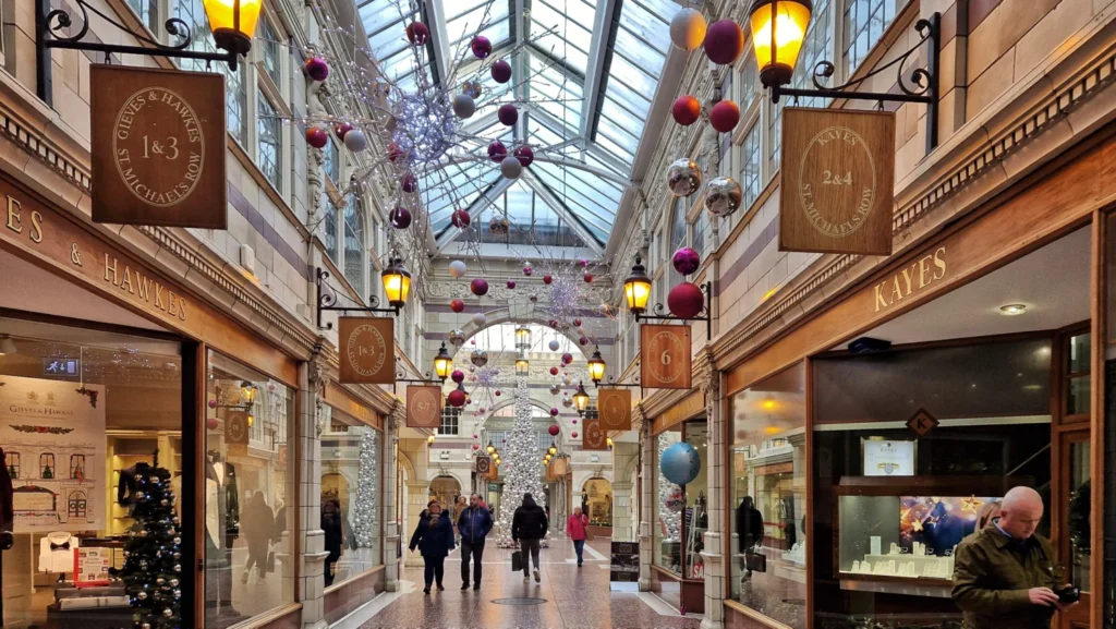 St Michael’s Row in Chester, England, with people walking through the historic shopping galleries and luxury boutiques beneath traditional architecture.