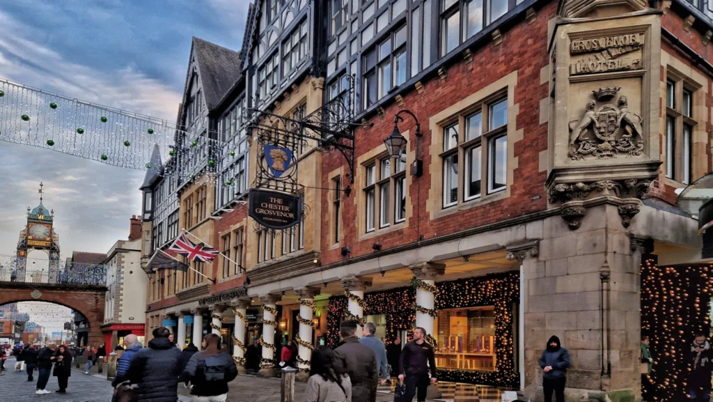The Chester Grosvenor hotel facade with the Eastgate Clock visible down the street, decorated with Christmas lights