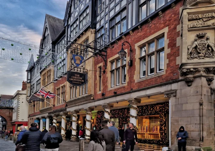 The Chester Grosvenor hotel facade with the Eastgate Clock visible down the street, decorated with Christmas lights