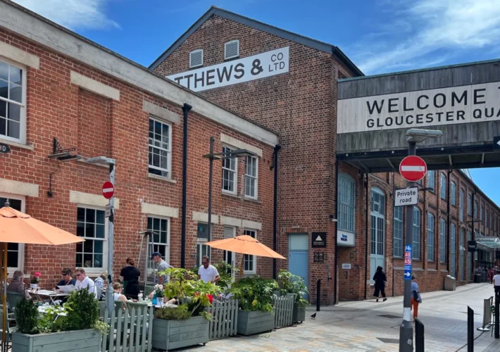 Victorian warehouses at Gloucester Quays with the entrance sign to the docks