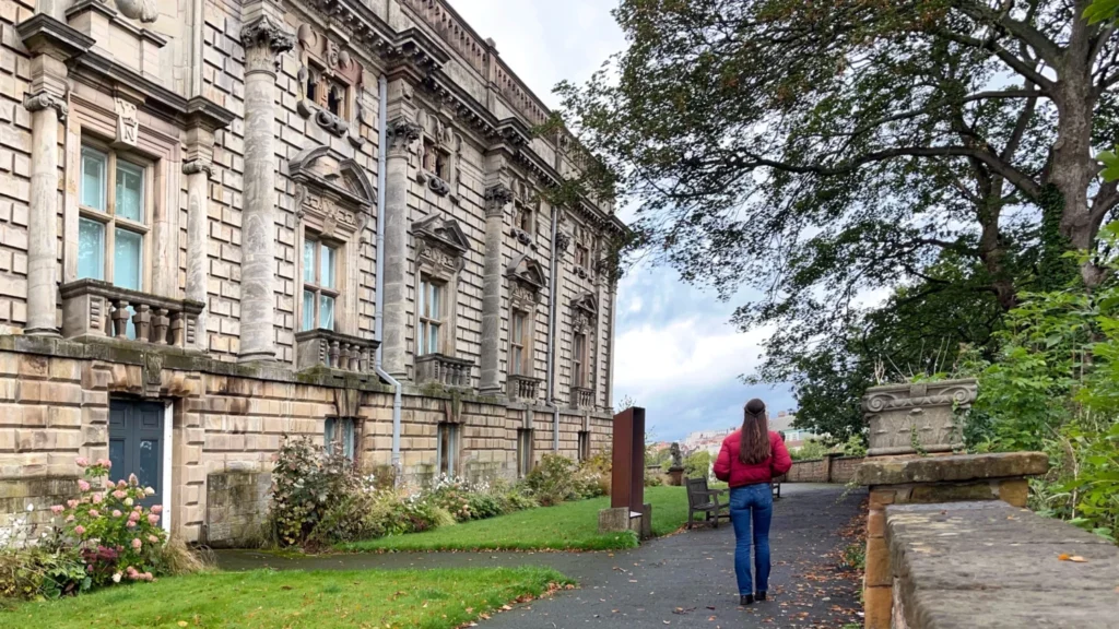Woman walking past the ornate stone facade of Nottingham Castle on a cloudy day