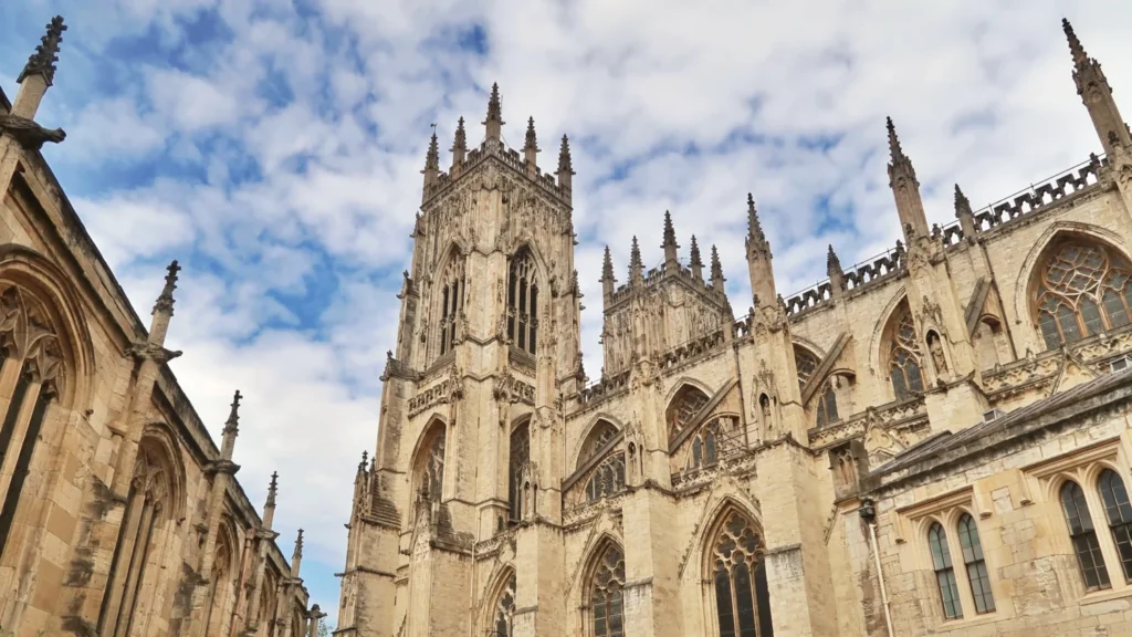 Close-up view of York Minster's gothic towers against a blue sky with clouds
