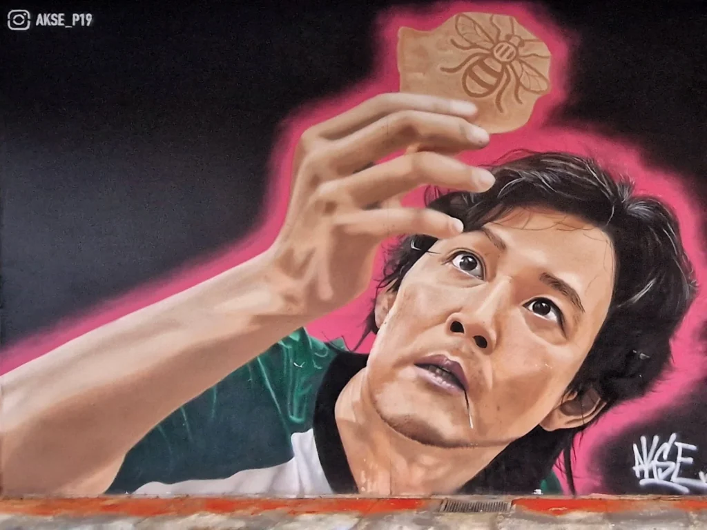 Akse P19 mural of Squid Game's Seong Gi-hun holding a dalgona bee biscuit on Copperas Street, Manchester