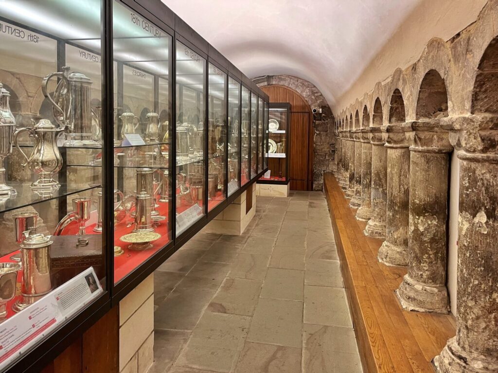 Glass cases of church silver in the Treasury, with a row of stubby Norman columns opposite