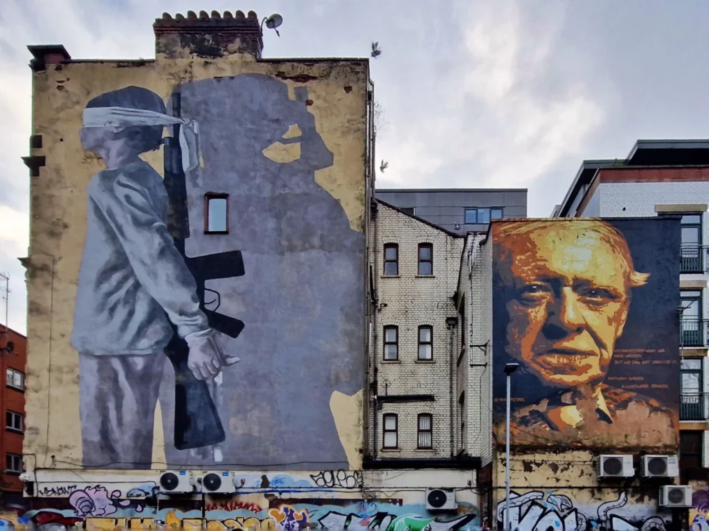 Hyuro's blindfolded child mural beside Tankpetrol's Anthony Burgess portrait on Brightwell Walk, Tib Street, Manchester