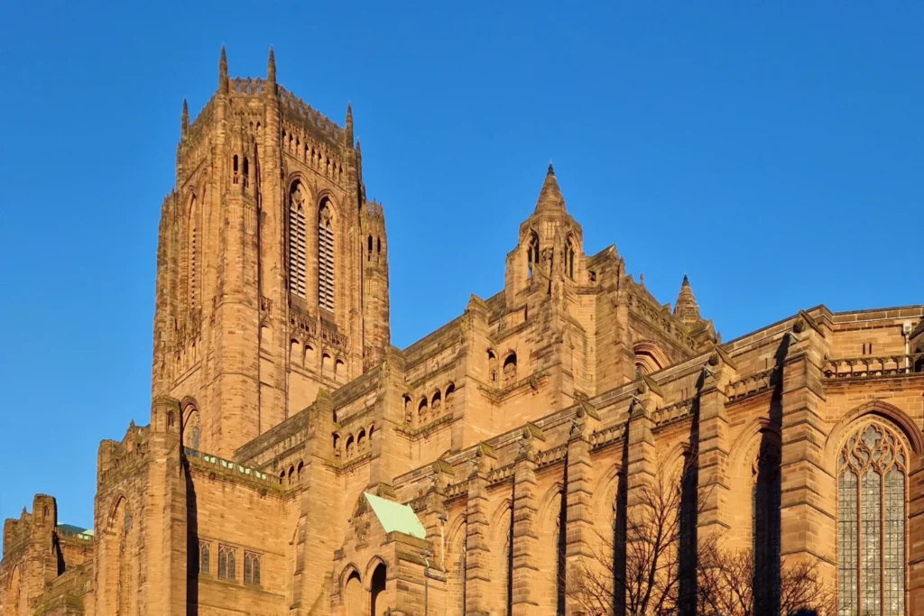 Sandstone Gothic Revival tower of Liverpool Cathedral under a clear blue sky