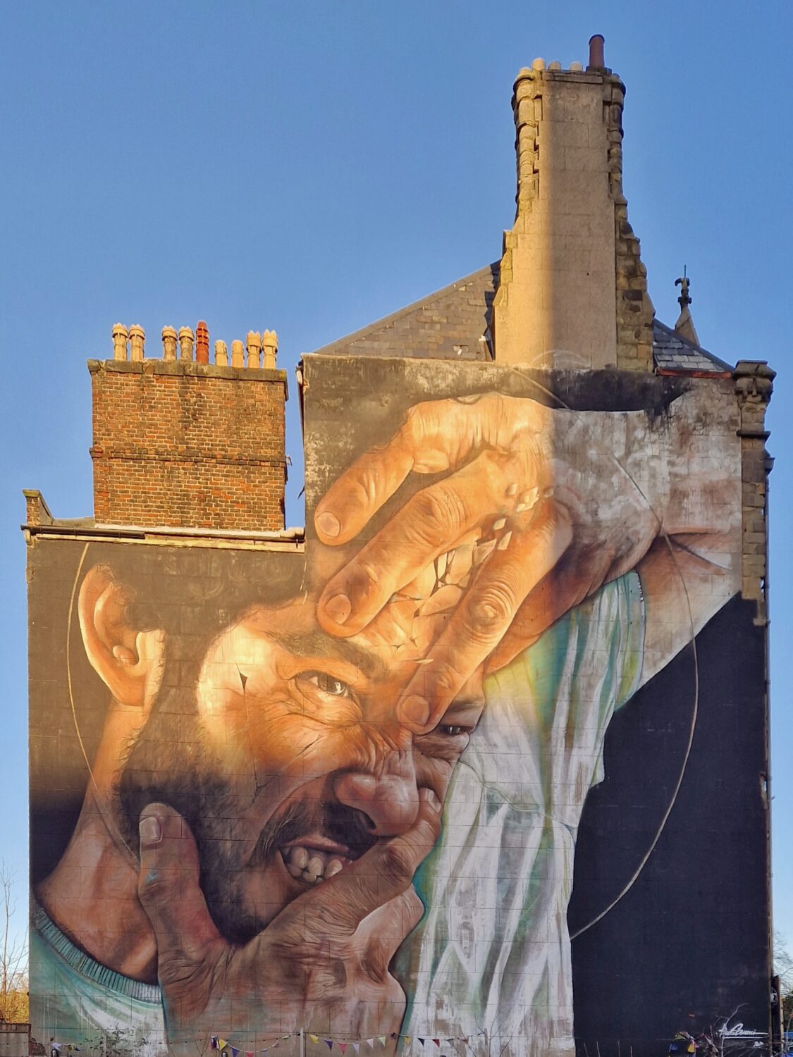 Liverpool street art mural of a man's face gripped by an oversized hand, Baltic Triangle