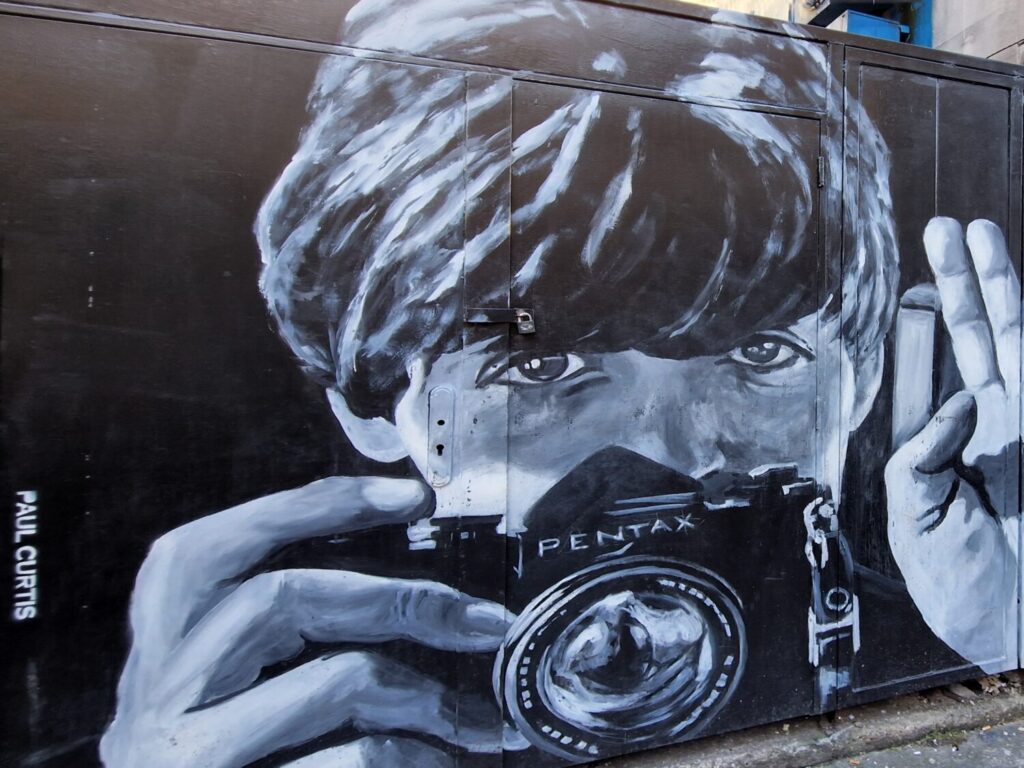 Black and white mural of a young Paul McCartney holding a Pentax camera on Harrington Street, Liverpool