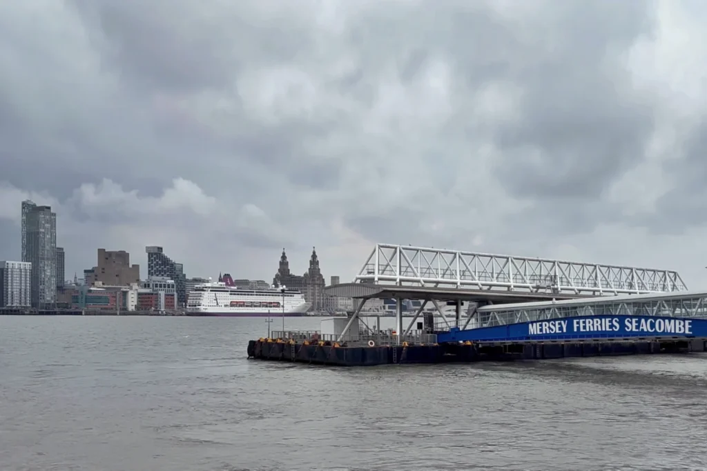 View of Liverpool's waterfront skyline, including the Royal Liver Building, seen across the River Mersey from the Mersey Ferries Seacombe terminal, with a cruise ship docked along the Pier Head.