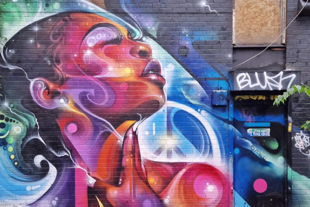 Mr Cenz street art mural of a woman's profile with swirling multicoloured hair on Church Street, Manchester